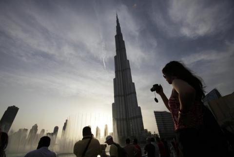 سائحون يلتقطون صورا لبرج خليفة في دبي - صورة من أرشيف رويترز. بيانات: نمو سياحة دبي قليلا في 2018 وزيادة الزائرين الصينيين 12%