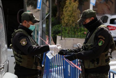 رجلا أمن يعقمان أيديهما أمام فندق انجل في بيت جالا حيث تتواجد الحالات المصابة بفيروس كورونا-تصوير وفا الشركات العاملة في مجال المعقمات تضاعف قدراتها الانتاجية