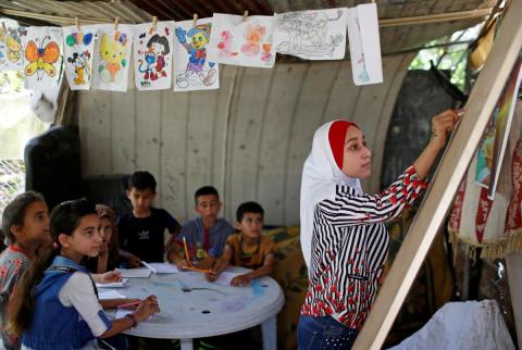 الطالبة الفلسطينية فجر حميد (13 عاما) تدرس لجيرانها اللغة العربية في قطاع عزة نظرا لغلق المدارس جراء فيروس كورونا يوم الثلاثاء. تصوير: محمد سالم - رويترز تلميذة في غزة تعلم أطفال الحي خلال إغلاق المدارس