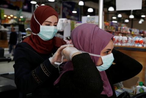 شابتان تعملان في أحد متاجر غزة ترتديان الكمامات والقفازات للوقاية من كورونا-تصوير وكالات تسجيل إصابات جديدة بفيروس كورونا في جنين وغزة