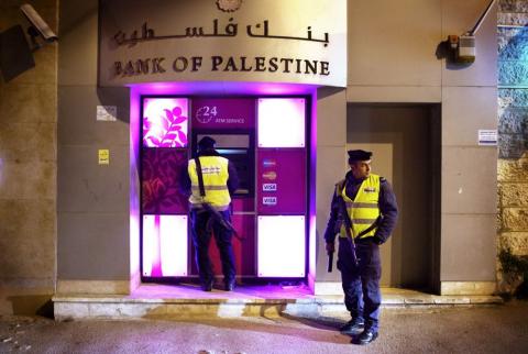 صورة توضيحية-رجل شرطة يستخدم الصراف الآلي لبنك فلسطين في بيت لحم-تصوير وكالات رواتب الموظفين العموميين الأحد المقبل