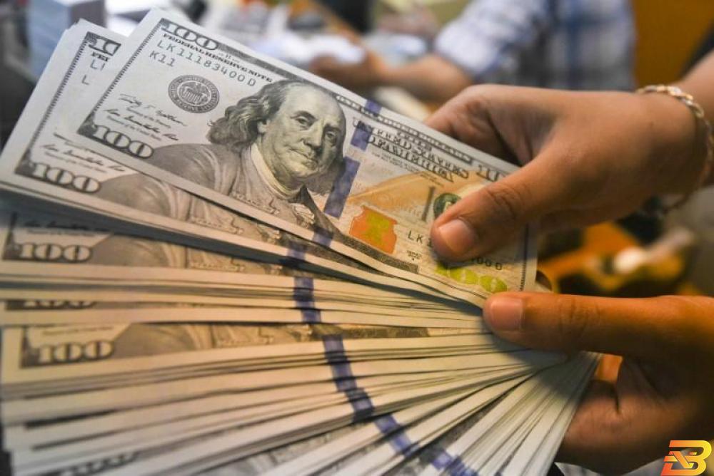موظفة تمسك بأوراق نقد فئة 100 دولار في مكتب تغيير عملات بجاكرتا - صورة من أرشيف رويترز الدولار يتراجع من أعلى مستوى في أسبوعين أمام سلة من العملات
