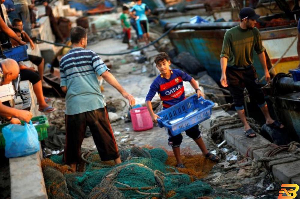 طفل فلسطيني يحمل صندوق أسماك قرب بحر غزة-أرشيف رويترز أسواق غزة خالية من الأسماك الطازجة!