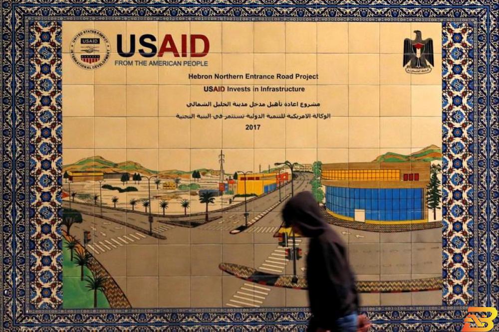 فلسطيني يمر أمام لافتة مشروع للوكالة الأمريكية للتنمية الدولية في الضفة الغربية يوم الجمعة. تصوير: موسى قواسمة - رويترز وقف مساعدات الوكالة الأمريكية للتنمية في الضفة وغزة