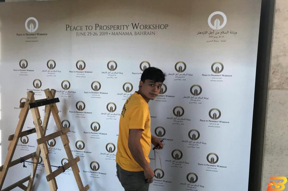 عاملون يثبتون يافطات في مكان إنعقاد الورشة الاقتصادية في البحرين-تصوير رويترز ’خطة كوشنير’ الاقتصادية: تكريس للاحتلال وتدمير للكيانية الفلسطينية