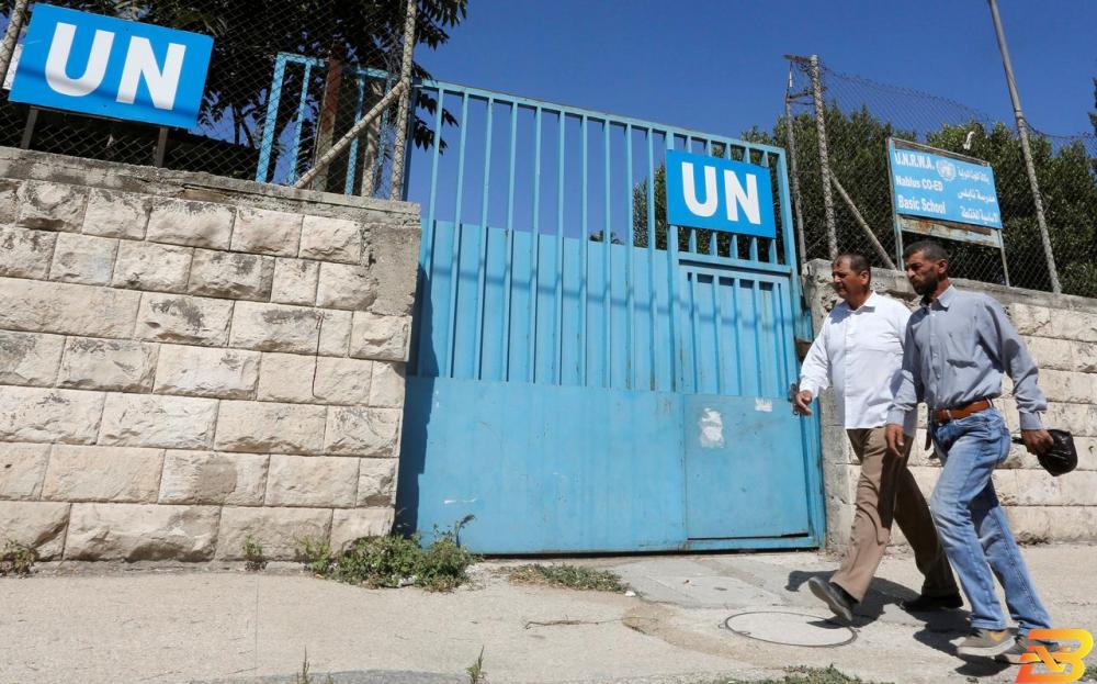 فلسطينيان يمرّان أمام مدرسة للأونروا في نابلس-أرشيف رويترز العجز المالي للأونروا يتراجع من 167 إلى 90 مليون دولار