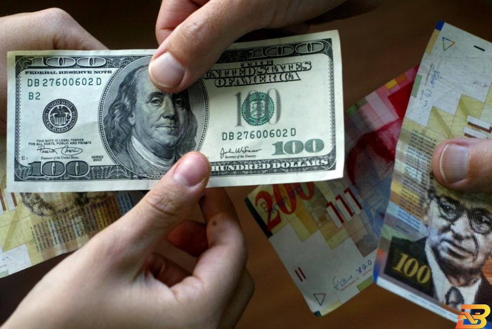 ورقة من فئة 100 دولار وأوراق من عملة الشيقل-أرشيف وكالات ثلاثة أسباب وراء تراجع الدولار أمام الشيقل