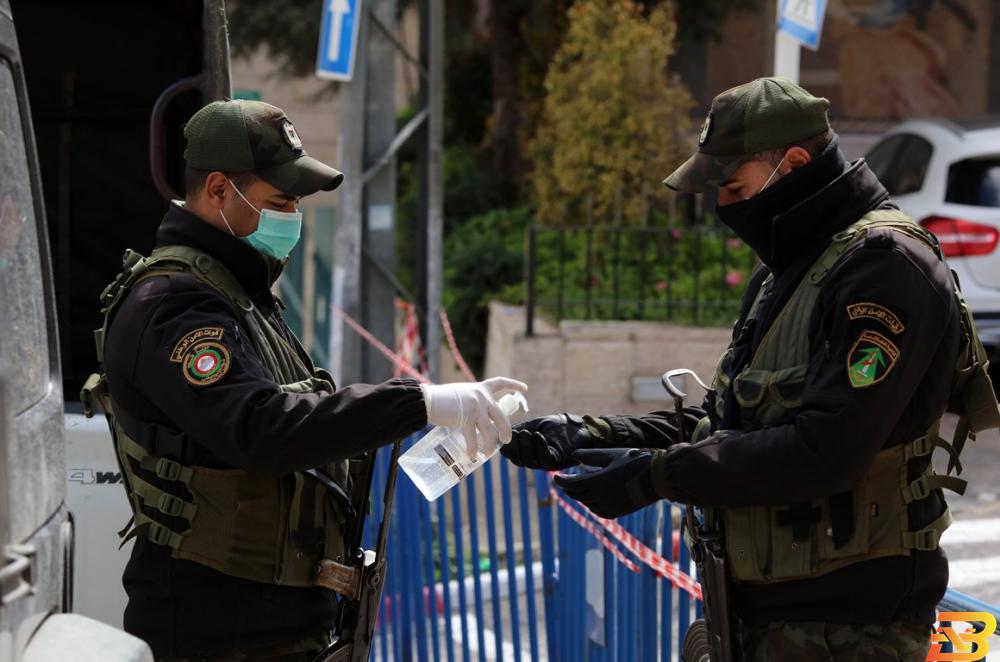 رجلا أمن يعقمان أيديهما أمام فندق انجل في بيت جالا حيث تتواجد الحالات المصابة بفيروس كورونا-تصوير وفا الشركات العاملة في مجال المعقمات تضاعف قدراتها الانتاجية