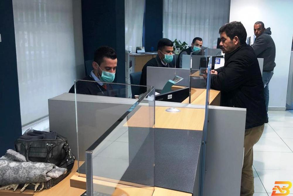 موظفو أحد البنوك في رام الله يرتدون كمامات واقية كإجراء احترازي تقليص ساعات دوام البنوك ومؤسسات الإقراض والصرّافين