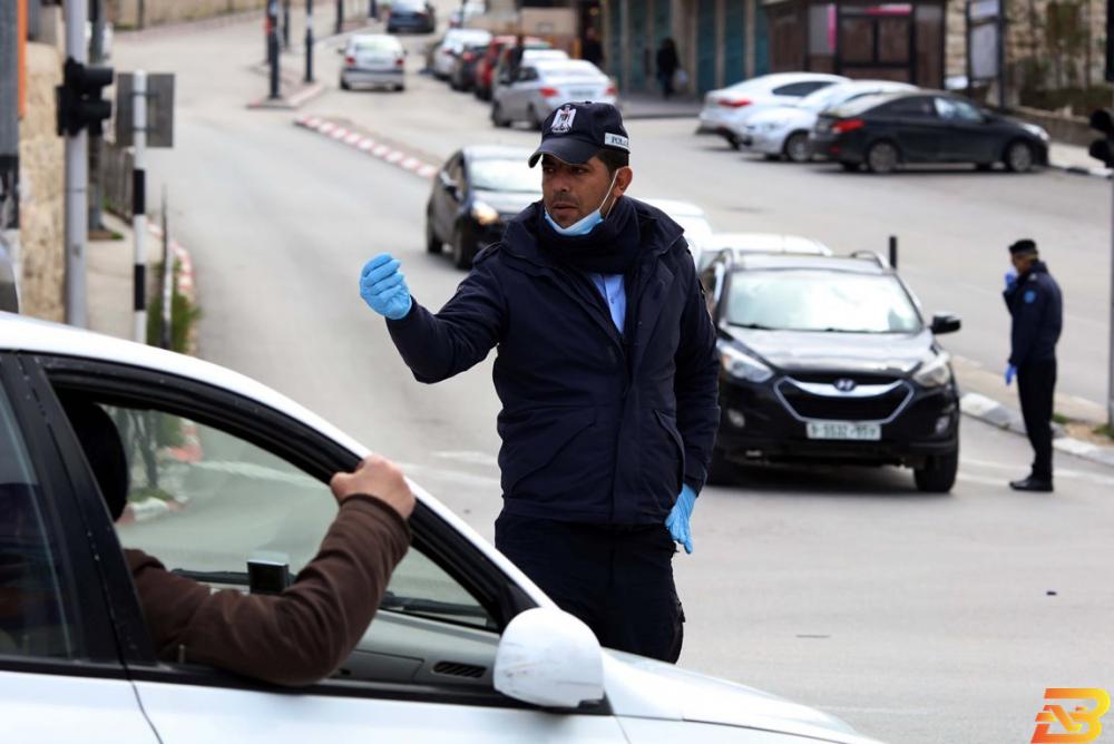 شرطي فلسطيني يوقف مركبة في بيت لحم ضمن الإجراءات الاحترازية لمواجهة فيروس كورونا-تصوير وفا إجراءات حظر التنقل والحجر المنزلي الإلزامي تدخل حيز التنفيذ