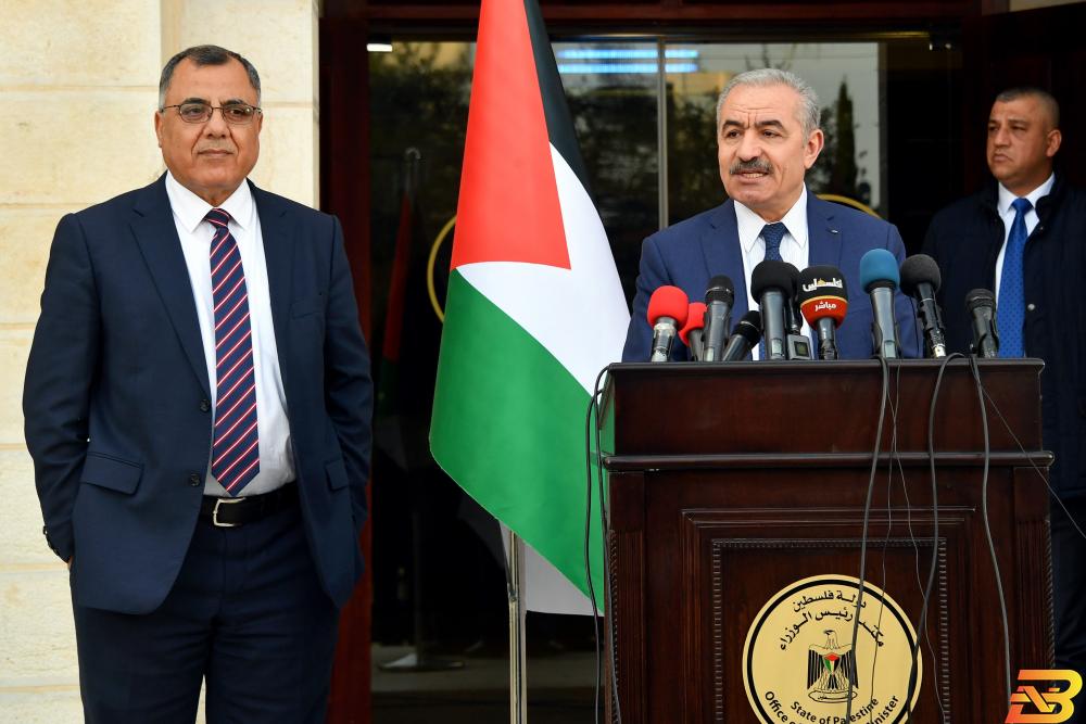 رئيس الوزراء محمد اشتية يتحدث خلال مؤتمر صحفي والمتحدث الرسمي باسم الحكومة يقف بجانبه فتح ’الدراي كلين’ ليس لكيّ بدلات المسؤولين!
