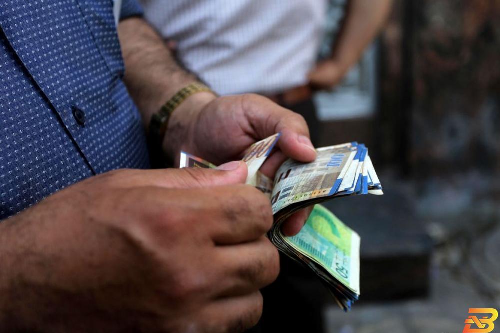 مواطن يعد أوراق نقدية من عملة الشيقل-تصوير وكالات مصدر لـBNEWS: نسبة صرف رواتب الموظفين ستحدد الإثنين