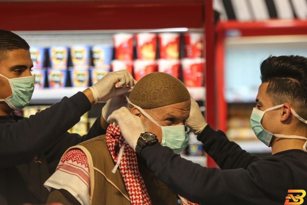 شابان في أحد المتاجر يساعدان رجل مسن على ارتداء كمامة-تصوير وكالات الشخرة: مئات المتاجر غير ملتزمة بالبروتوكول الصحي