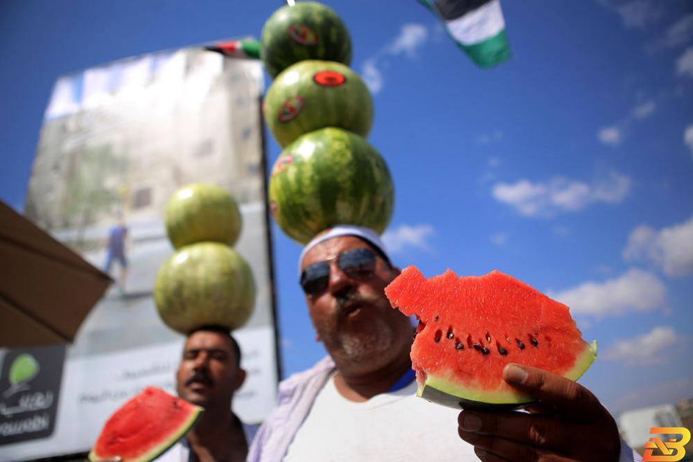بائع فلسطيني يضع البطيخ على رأسه في محاولة لتسويقه-تصوير وكالات بطيخ الأغوار.. تسويق على وقع الغناء