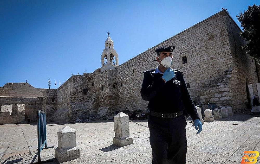 شرطي فلسطيني يرتدي كمامة طبية أمام كنيسة المهد في بيت لحم-تصوير وكالات كورونا.. لا بوادر لعودة السياحة في فلسطين قريبا