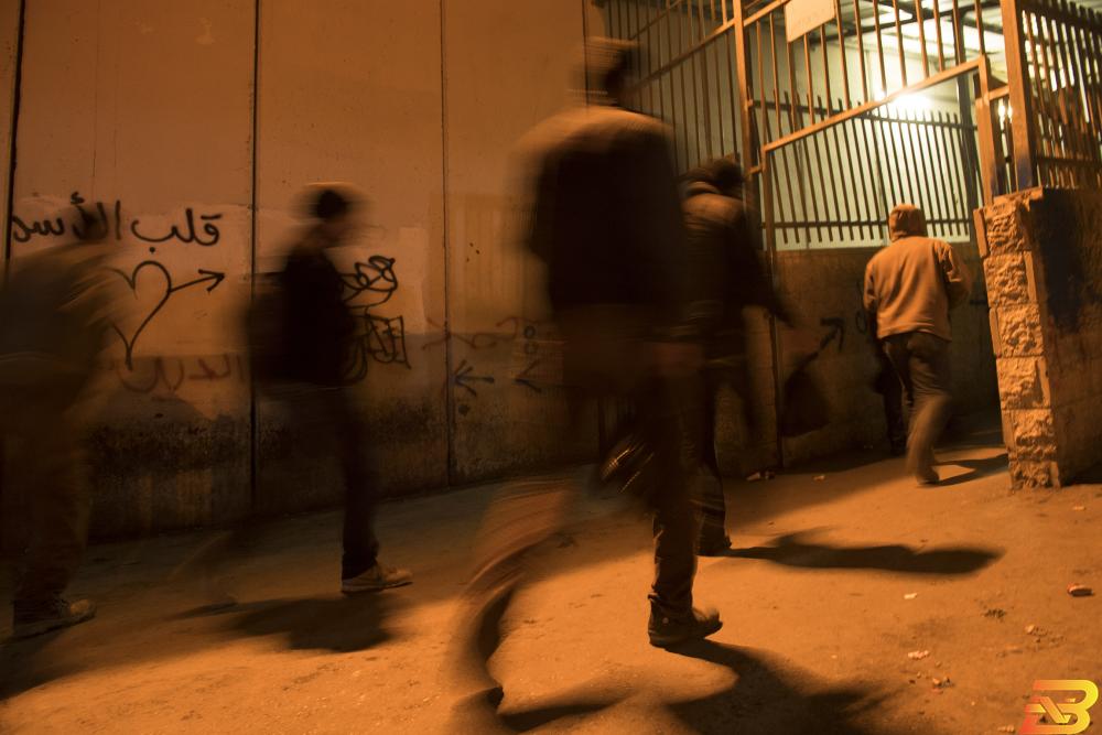 عمال فلسطينيون يقطعون أحد الحواجز الإسرائيلية في طريقهم للعمل-أرشيف وكالات ماس: 122 مليون شيقل أرباح سماسرة تصاريح العمل في 2018