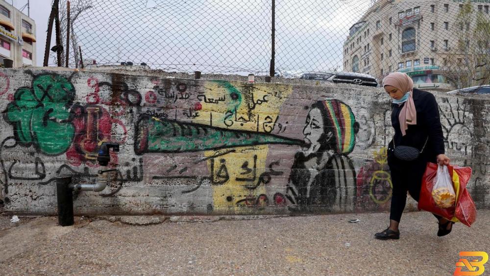 صورة توضيحية-مواطنة تسير أمام جدارية في رام الله-تصوير أ ف ب 9 ملايين دولار منحة من البنك الدولي لدعم القطاع الخاص